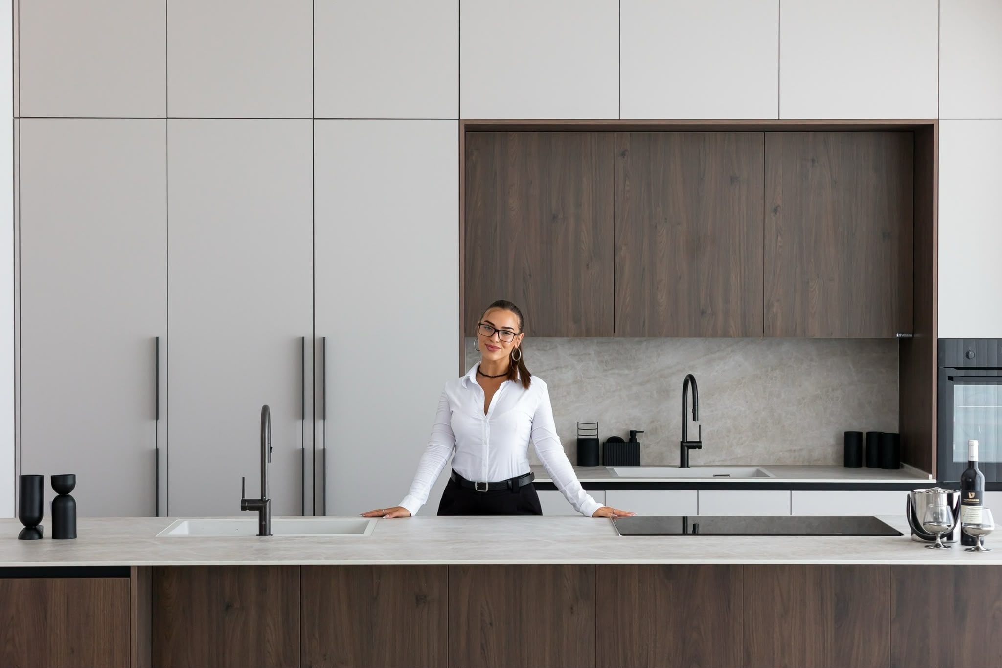 Full elevation of the mist-grey kitchen: tall handle-less cabinetry around a dark walnut niche