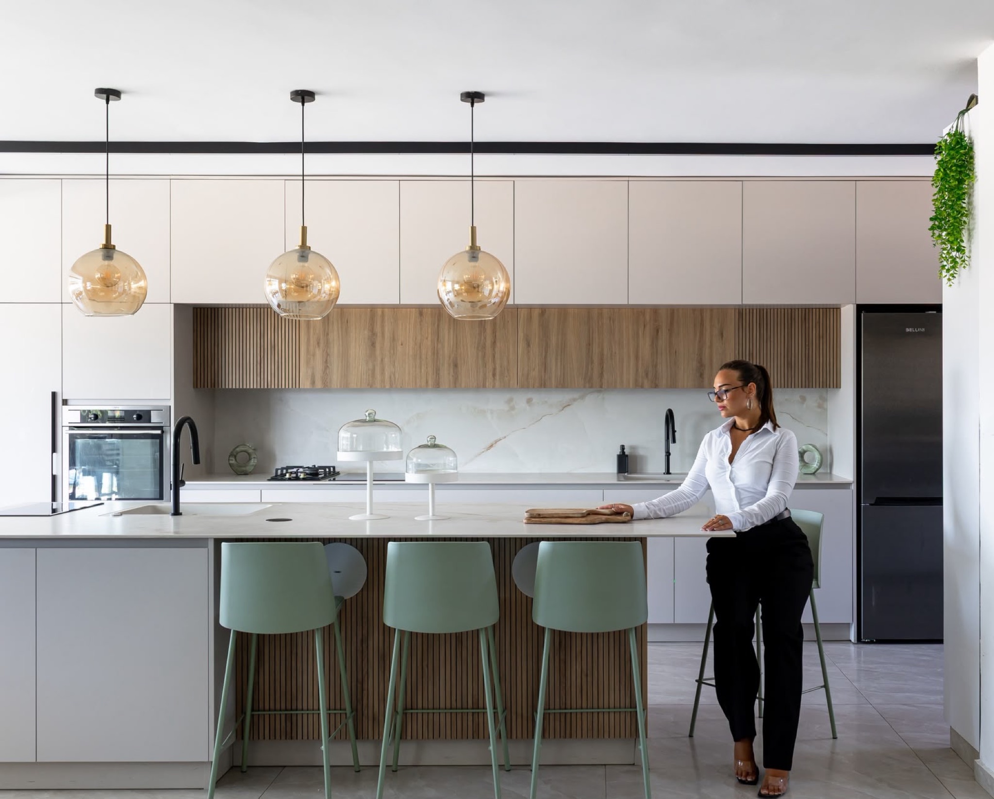 White kitchen run with fluted oak cabinets and a marble-veined splashback