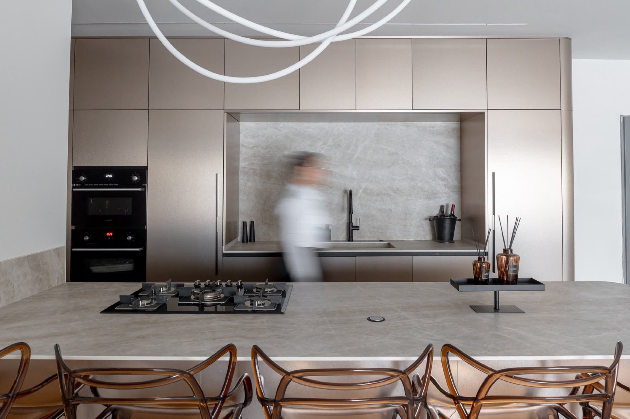 The cooking wall with black tap and warm oak upper cabinets